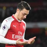Mesut Ozil sedang mengangkat kedua tangannya saat bermain bersama Arsenal